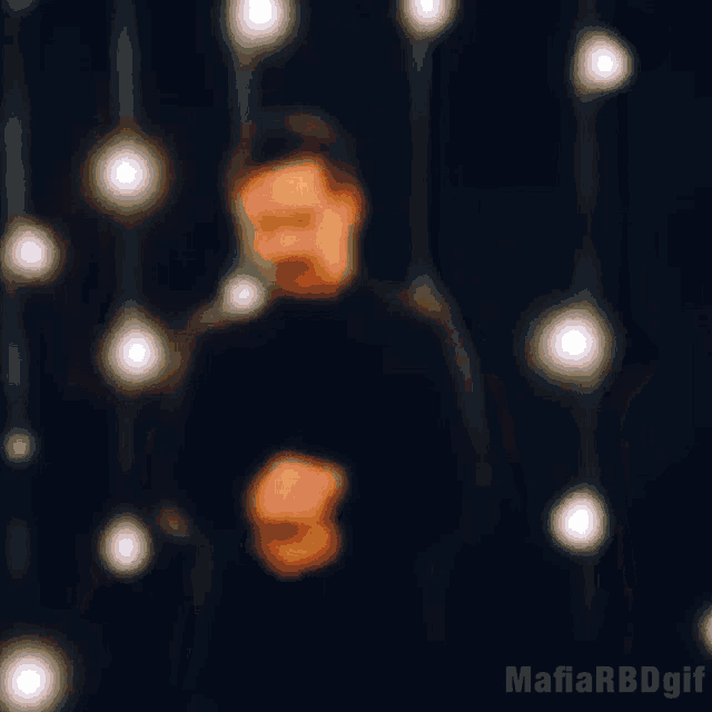 a man with a mustache is standing in front of a bunch of light bulbs and a mafia rbd gif