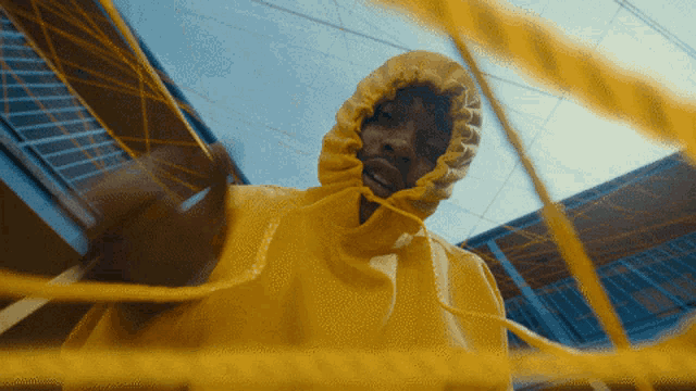 a person wearing a yellow hoodie is standing in front of a yellow rope