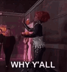 a drag queen is dancing on a stage in a dark room while holding a drink in her hand .