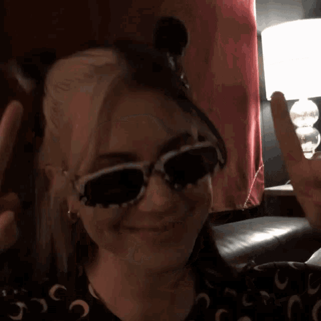 a girl wearing sunglasses and a mickey mouse headband is giving a peace sign