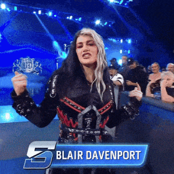 a female wrestler named blair davenport holds a trophy in front of a crowd
