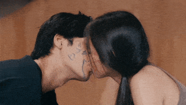 a man and a woman kissing with a drawing of a heart on the man 's face