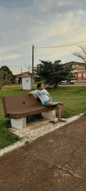 a young man sits on a bench with his legs crossed and his shirt says beatles