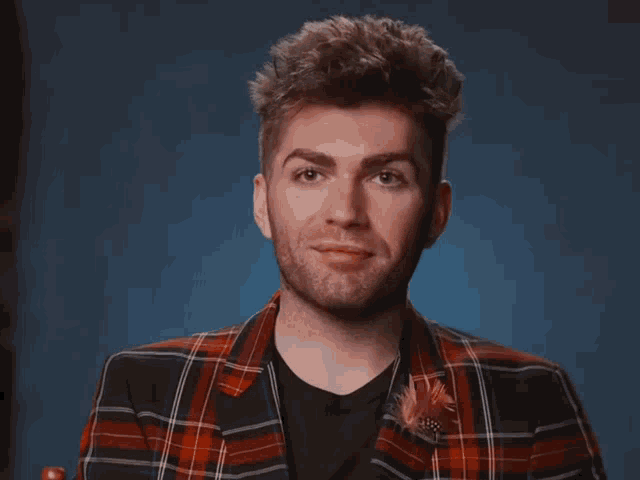 a man wearing a plaid jacket and a black shirt is smiling