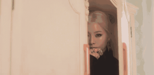 a woman is peeking out of a closet with a ring in her hand .