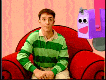 a man in a green striped shirt sits in a red chair next to a purple mailbox