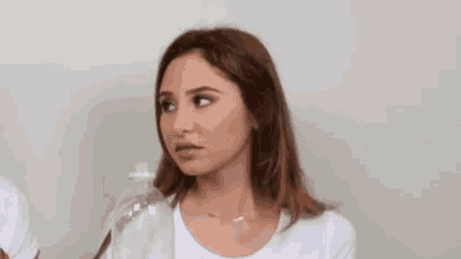 a woman is holding a bottle of water in her hand and making a funny face .