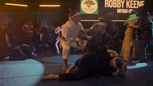 a group of people are practicing martial arts in a gym while a light shines through the ceiling .