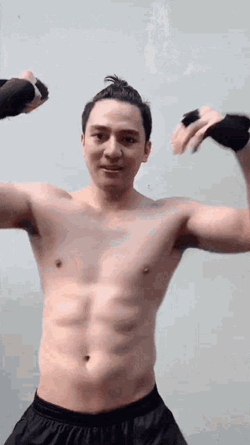 a shirtless man is flexing his muscles while wearing boxing gloves