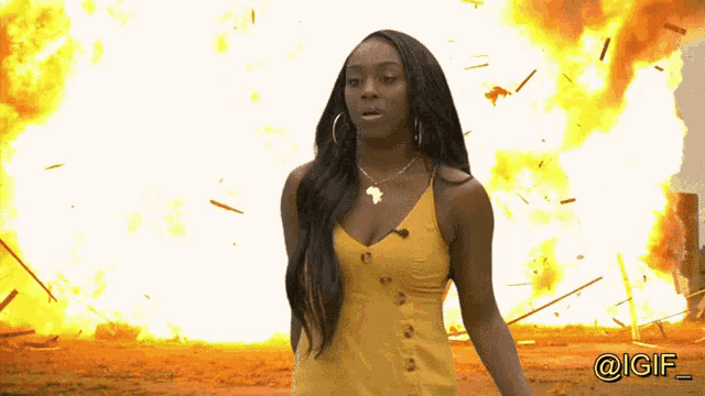 a woman in a yellow dress is standing in front of an explosion with the hashtag @igf_