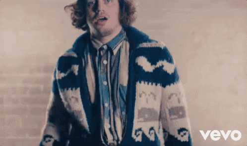 a man wearing a blue and white sweater is standing in front of a vevo logo