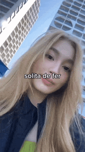 a woman with long blonde hair is standing in front of a building and the words solita de fer are on her face