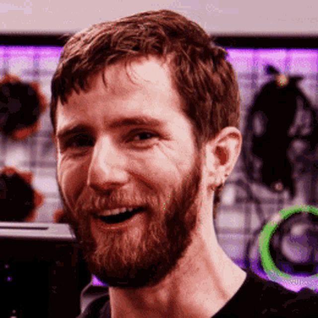 a man with a beard wearing a black shirt smiles for the camera