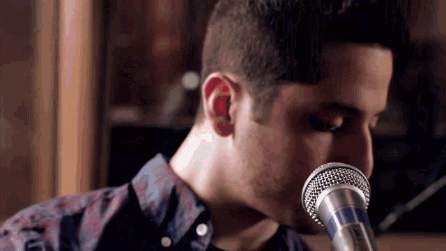 a close up of a man singing into a microphone with his eyes closed