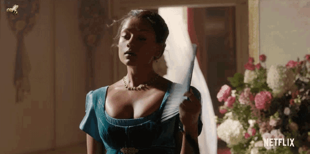 a woman in a blue dress is holding a fan in front of a netflix logo .