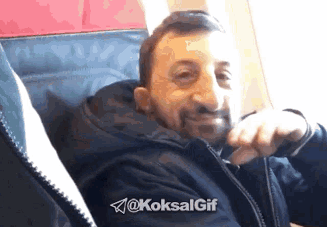 a man with a beard is sitting on an airplane with the hashtag @koksalgif above him