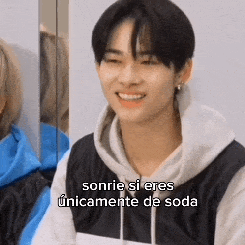 a young man in a hoodie is smiling and talking in spanish .