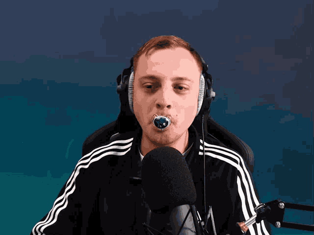 a man wearing headphones and a pacifier in his mouth talks into a microphone