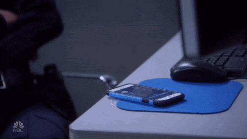 a cell phone on a blue mouse pad with the nbc logo