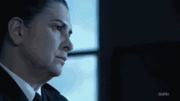 a close up of a woman 's face in a suit and tie looking out a window .