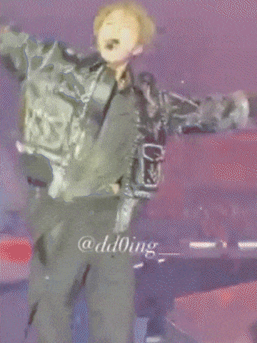 a man in a camouflage jacket is dancing on a stage in front of a crowd .