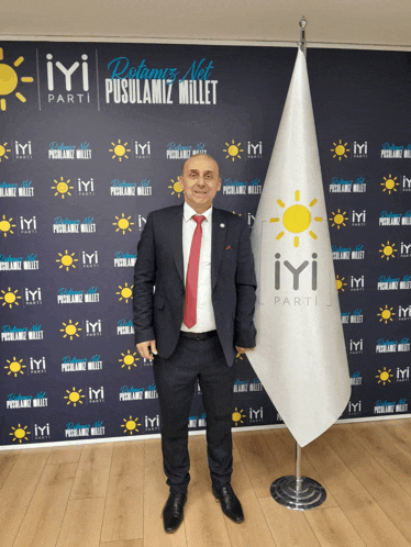 a man in a suit stands in front of a wall that says iyi parti on it