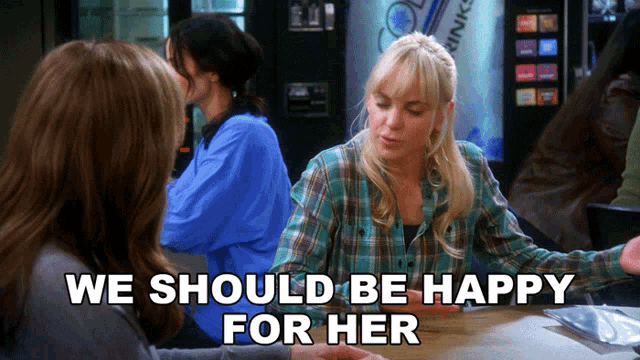 two women are sitting at a table with the words we should be happy for her