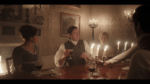 a group of people are sitting at a table with candles