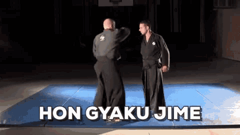 two men standing on a mat with the words hon gyaku jime