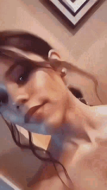 a woman without a shirt is taking a selfie in front of a wall .