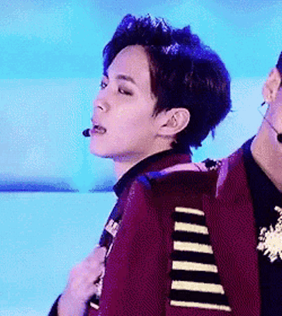 a man in a red jacket with a microphone in his mouth is standing next to another man .