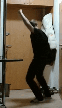 a man in a black shirt is dancing in a hallway with his arms in the air