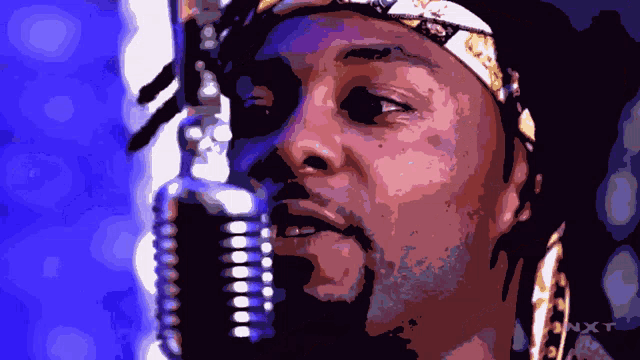a close up of a man 's face with a microphone in front of him and the word nxt on the bottom right