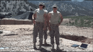 two soldiers pose for a picture in front of a mountain