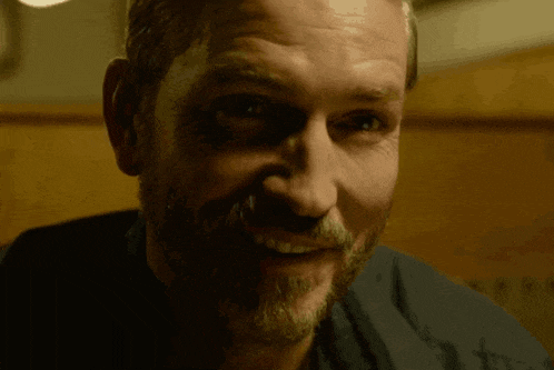 a man with a beard is smiling with his mouth open