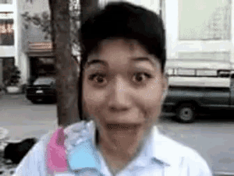 a man is making a funny face with his mouth open in front of a truck .