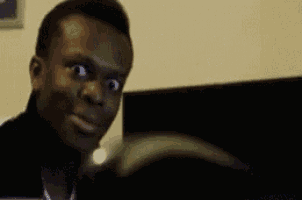 a man is making a funny face while sitting in front of a computer screen .