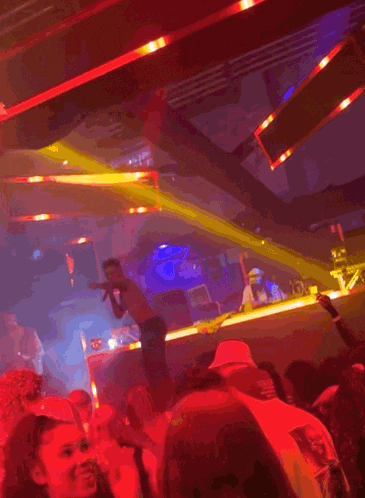 a man stands on a stage in front of a crowd at a party