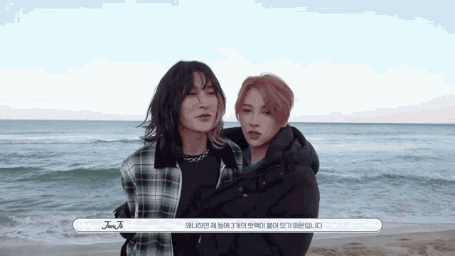 two people standing next to each other on a beach with the name jun ji written on the bottom right corner