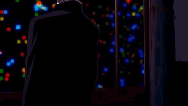 a man in a suit stands in front of a window looking out