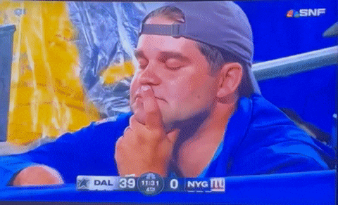 a man covering his nose with his finger while watching a game