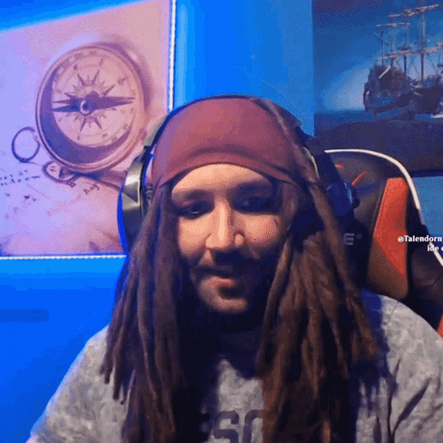 a man with dreadlocks is wearing headphones and a bandana in front of a compass