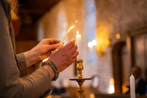 a woman holds a lit candle in her hands