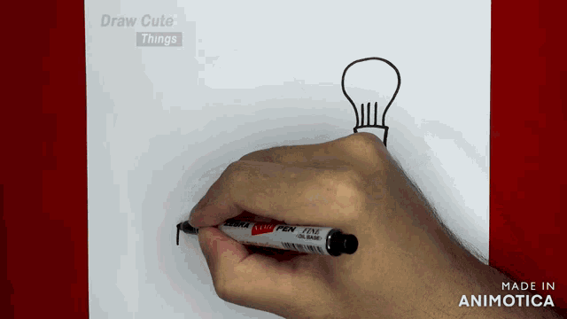 a person is drawing a light bulb on a piece of paper