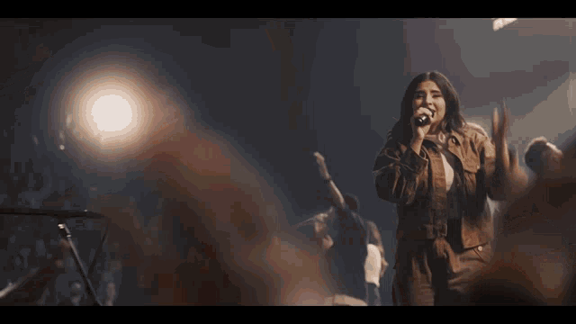 a woman is singing into a microphone in front of a crowd of people