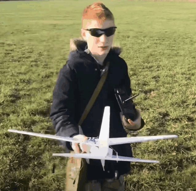 a boy wearing sunglasses is holding a model airplane in his hands