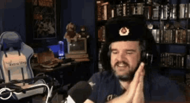 a man wearing a hat and headphones is giving a high five while sitting in front of a microphone .