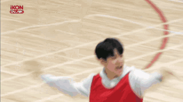 a man in a red shirt is talking on a television screen with the word ikon on it