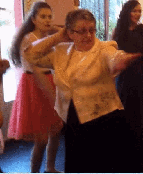 a woman in a white jacket is dancing with a girl in a pink dress