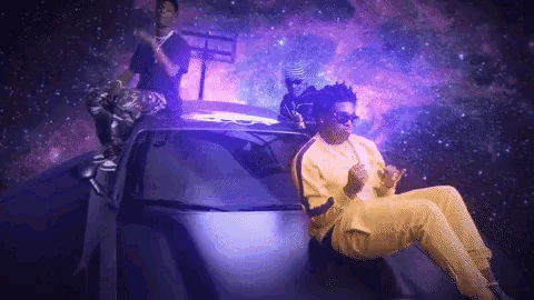 a man in a yellow outfit is sitting on top of a car